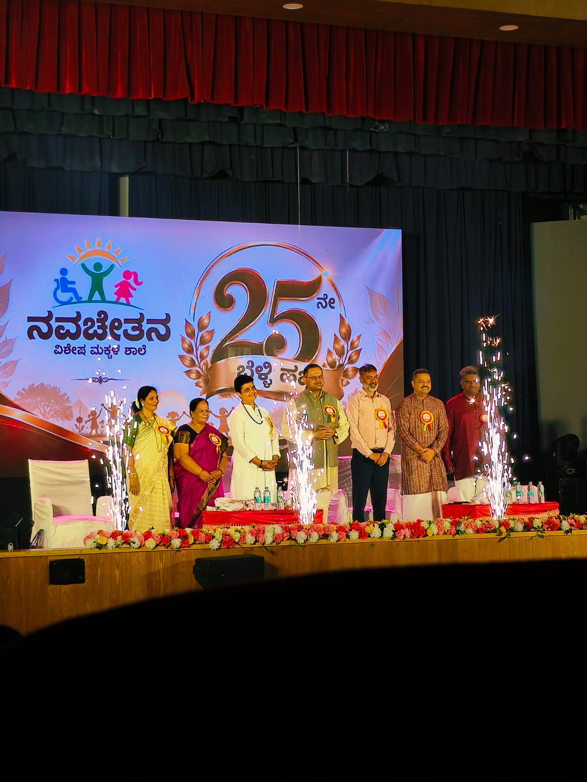 Trust dignitaries and chief guests light sparklers on stage beneath the 25th Anniversary backdrop