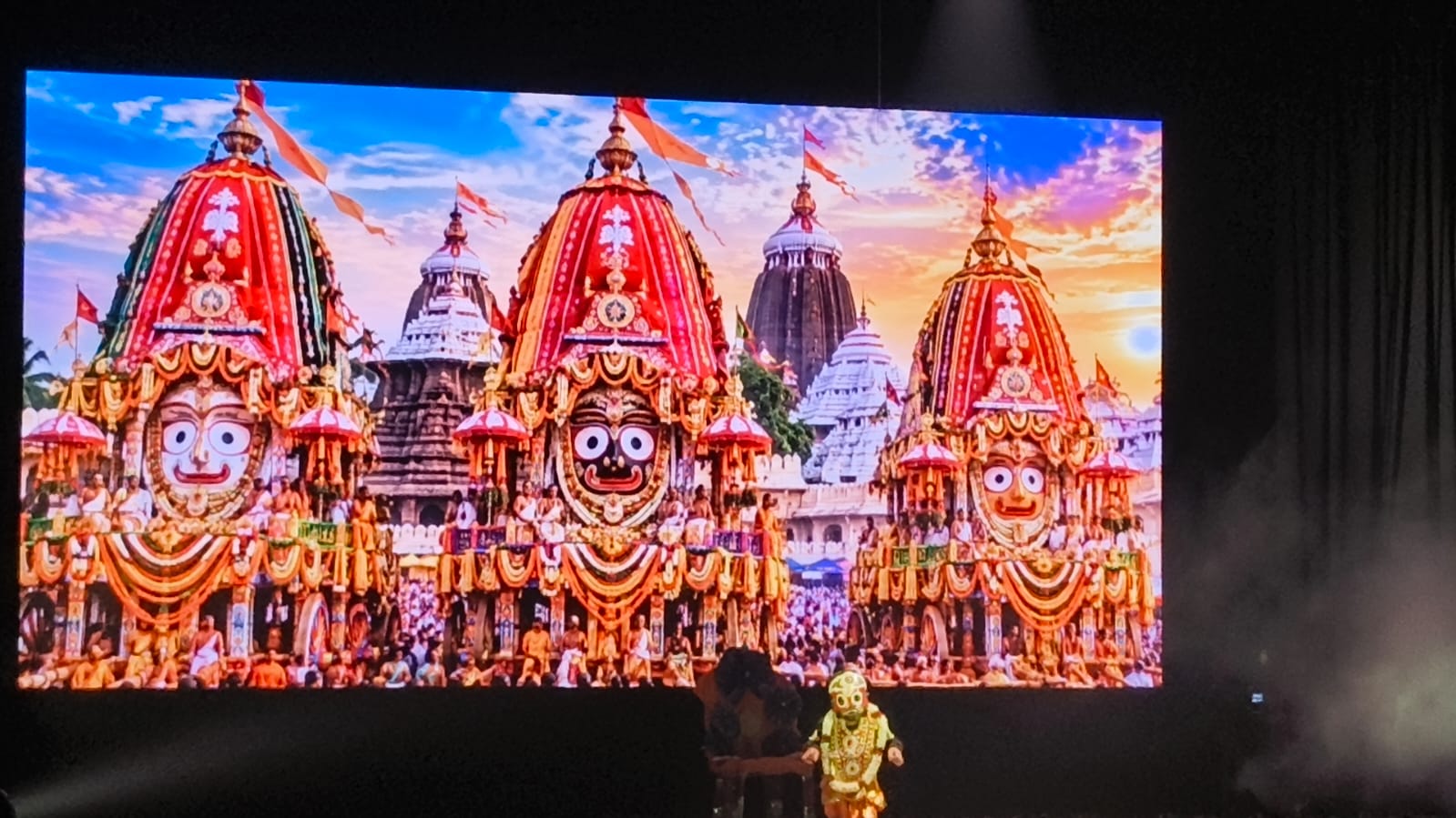 Visuals of the Jagannath Rath Yatra displayed during a devotional segment of the celebration